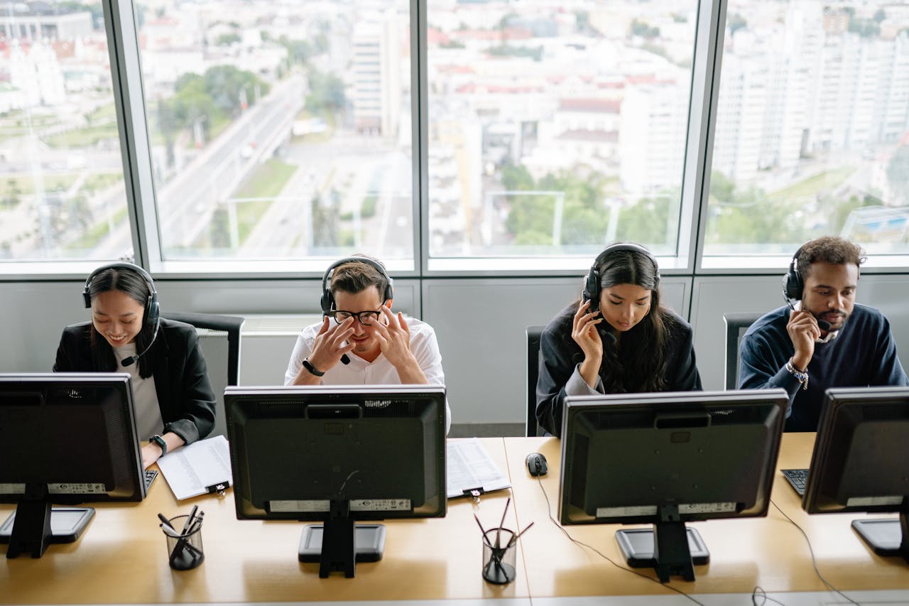 Home Group of diverse call center employees working at computers in a modern office setting.